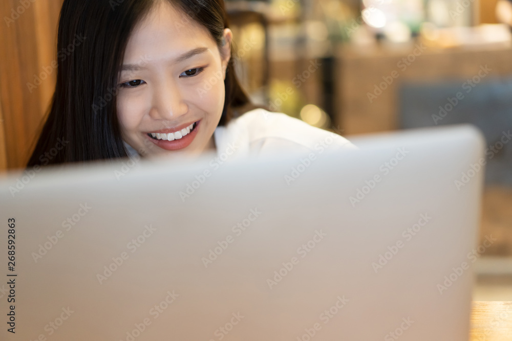 Happy young Asian woman using phone and working with a laptop in the coffee shop cafe office. Happy young Asian woman using phone and working with a laptop in the coffee shop cafe office.