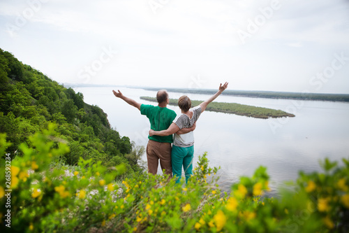 elderly couple on the top of mountain with hands up. Senior couple walking in nature © ulza