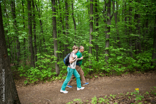 elderly couple with backpack hiking in forest. Senior couple walking in nature