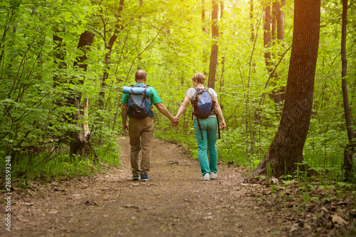 elderly couple with backpack hiking in forest. Senior couple walking in nature