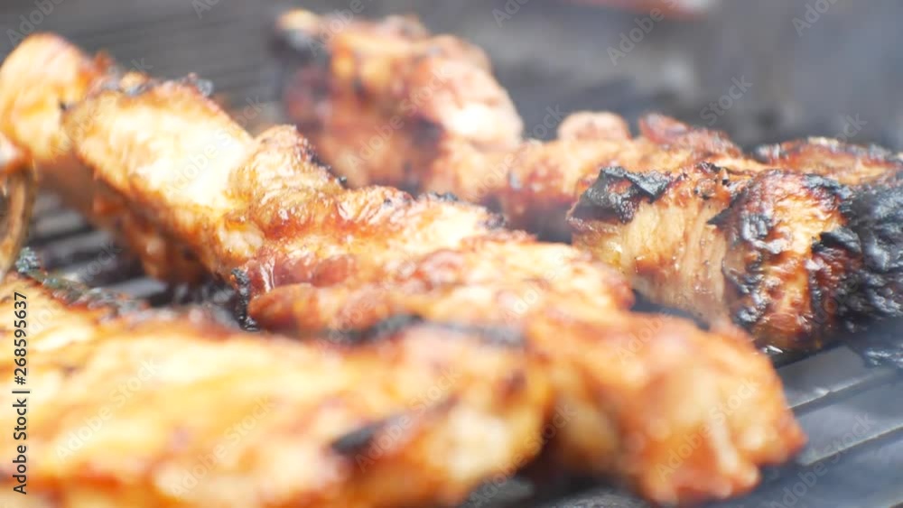 Close up, static shot on succulent, juicy glazed pork fillet sizzling & bubbling over hot, blazing barbecue. Grease dripping onto flames creating hot smoke, Female presses meat with tongs. Close up, static shot on succulent, juicy glazed pork fillet sizzling & bubbling over hot, blazing barbecue. Grease dripping onto flames creating hot smoke, Female presses meat with tongs.
