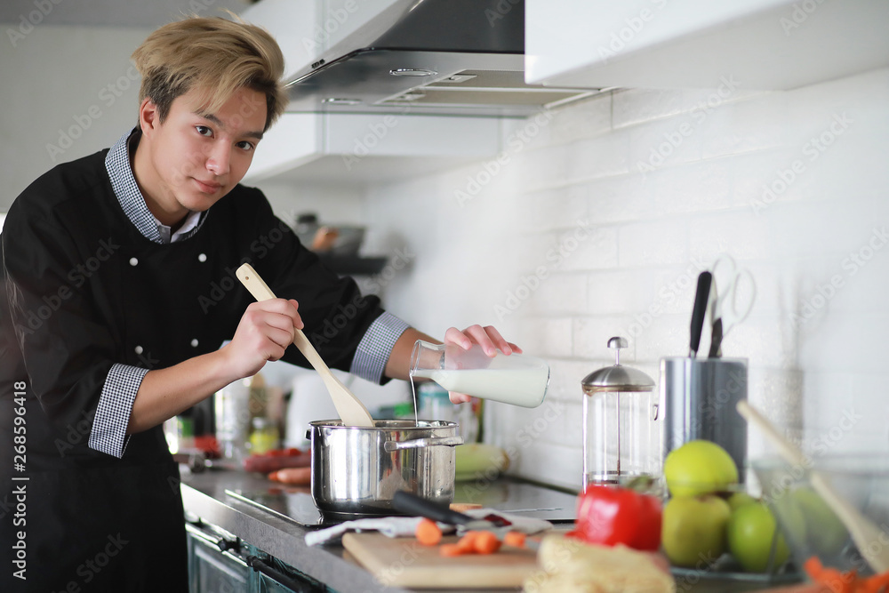 Asian cook in the kitchen prepares food in a cook suit Asian cook in the kitchen prepares food in a cook suit