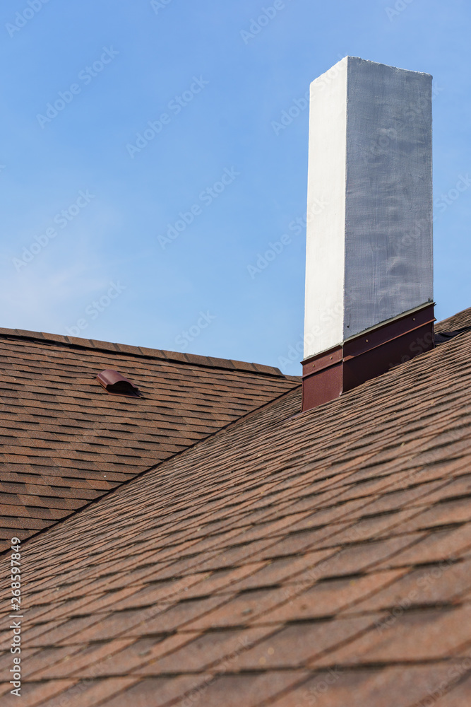 Asphalt tile roof with chimney on new home under construction Asphalt tile roof with chimney on new home under construction
