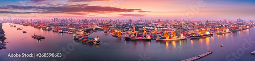 Aerial panoramic view of Logistics and transportation of Container Cargo ship and Cargo plane with working crane bridge in shipyard at sunrise, logistic import export and transport industry background photo