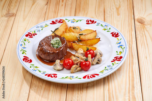 steak with baked potatoes on wooden background