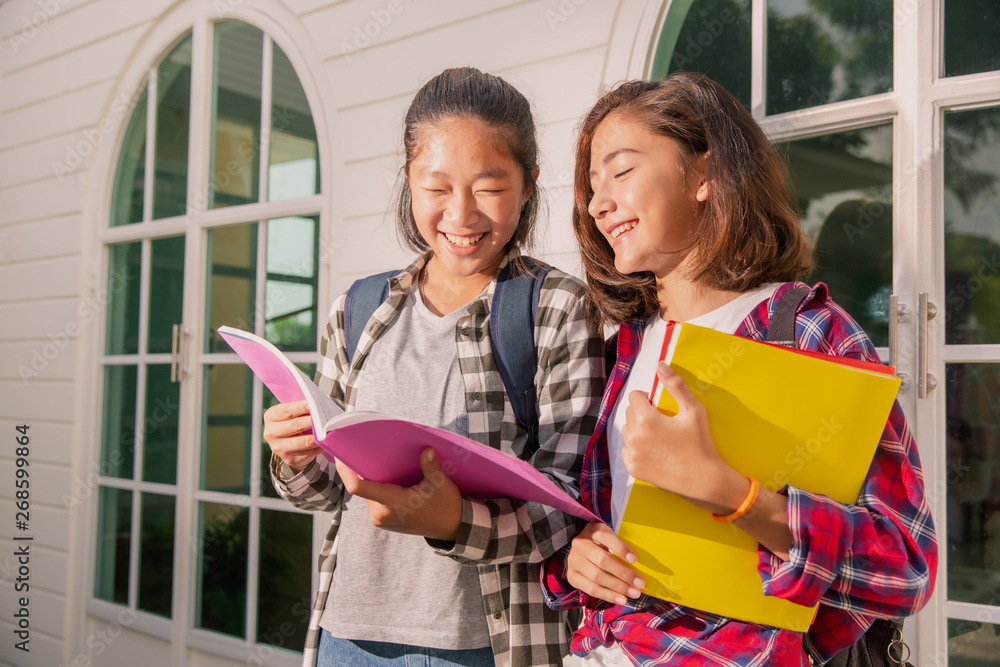 Two teenage asia and european student friends girls happy going to college or school