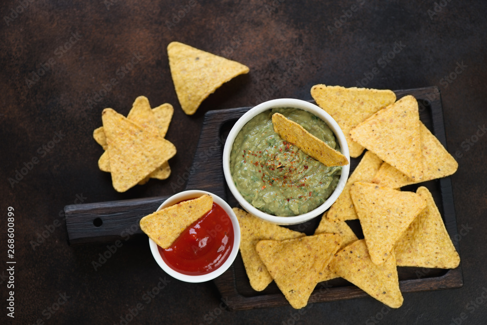 Wooden serving tray with nachos chips and dipping sauces, flatlay over dark brown metal background Wooden serving tray with nachos chips and dipping sauces, flatlay over dark brown metal background