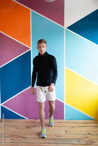 sports guy on the background of a colored wall going forward.