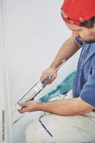 Worker using silicone for walls and door frame inside the house - renovation fixes.