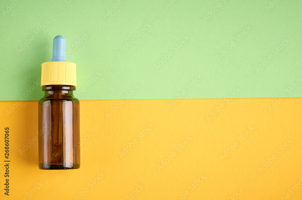 Nasal drops bottle composition, glass bottle on yellow and green background