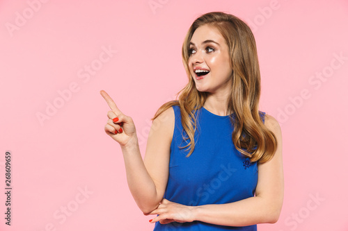 Happy young pretty woman posing isolated over pink wall background showing copyspace.