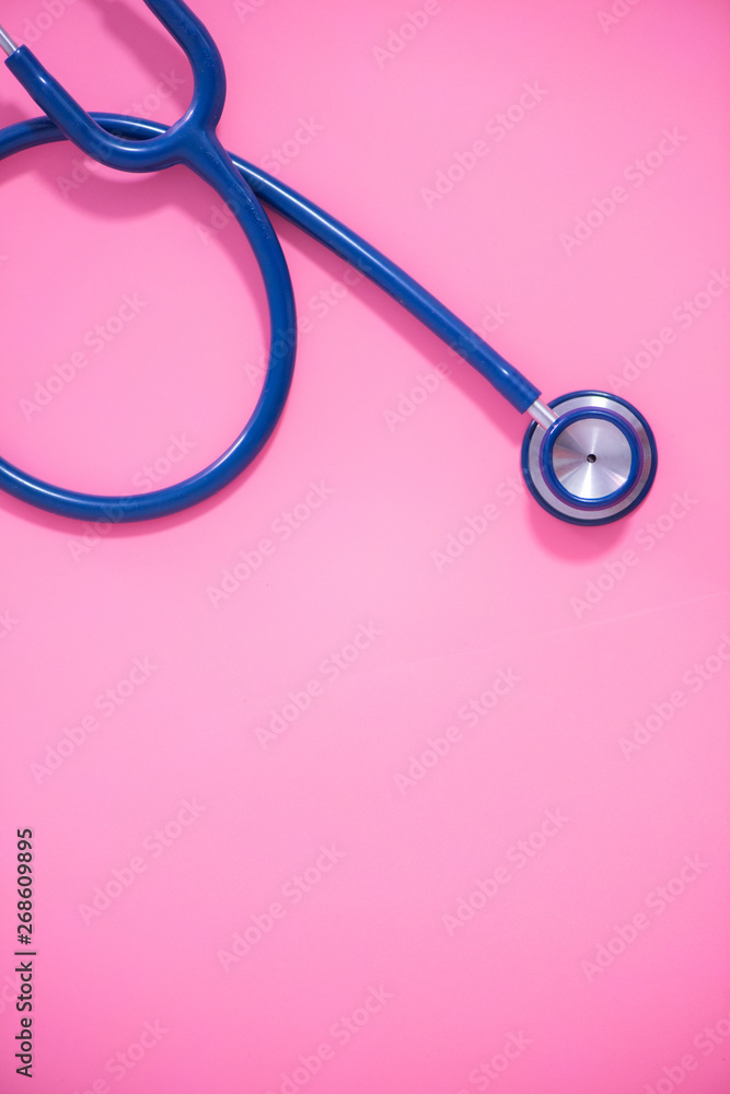 Fototapeta premium Top view blue stethoscope on pink background. For check heart or health check up concept