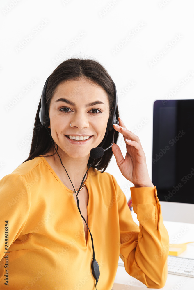 Photo of caucasian phone operator woman wearing microphone headset sitting in office and speaking with client Photo of caucasian phone operator woman wearing microphone headset sitting in office and speaking with client