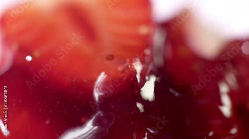 Macro strawberry jam dessert syrup pouring on moving sticky spoon. Cooking home canned confiture food.