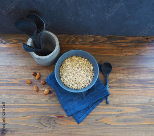 Bowl of oatmeal, wooden spoons and nuts on the table.