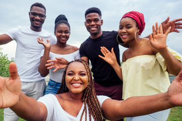 group of five friends female and male taking selfie on camera smartphone and having fun outdoors lifestyle near lake