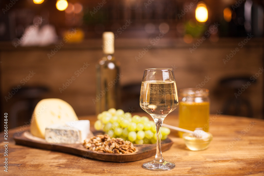 Glass of white wine ,cheese and grapes on old wooden table
