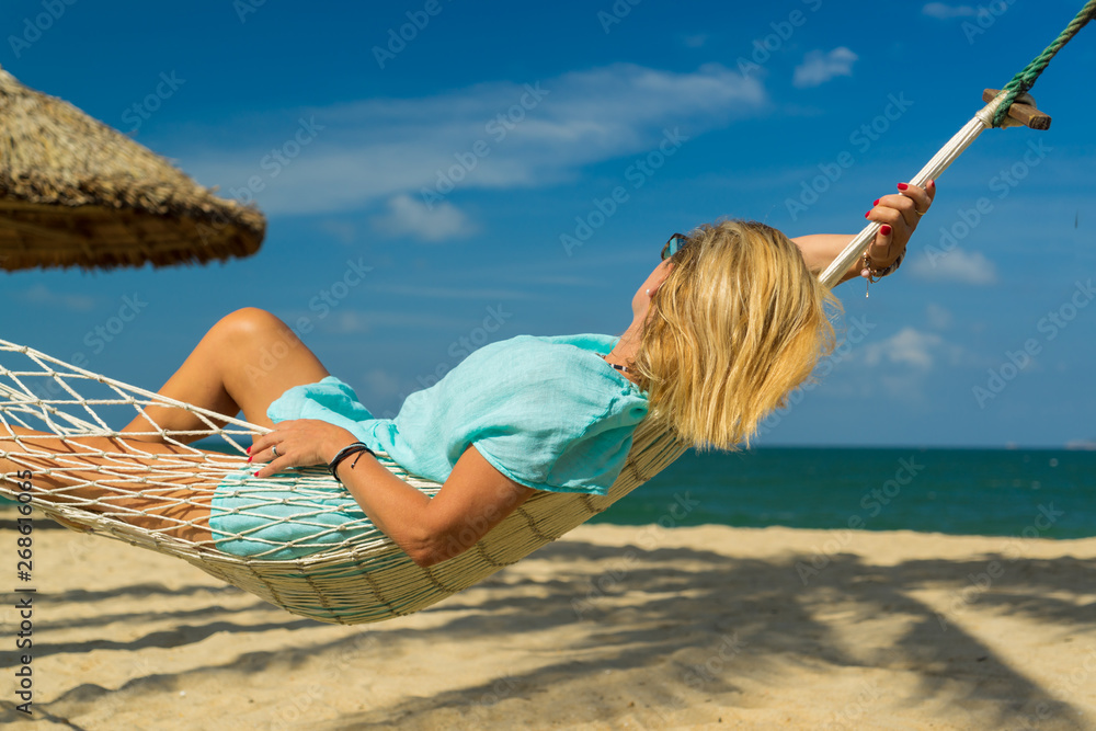 Naklejka premium Woman sitting in hammock on the beach.