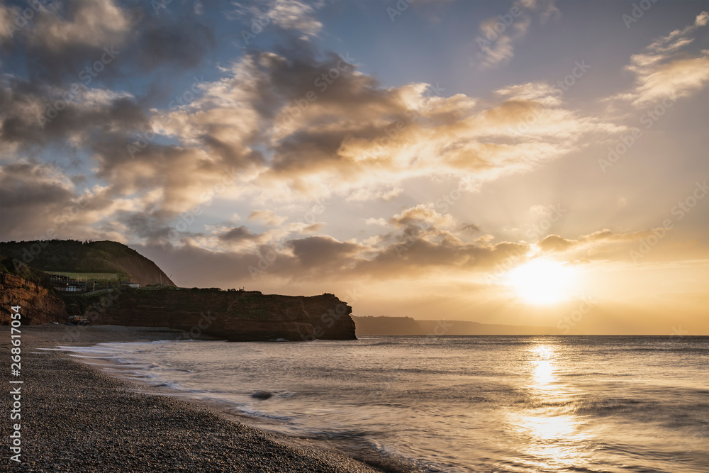 Stunning sunrise landscape image of Ladram Bay beach in Devon England with beautiful rock stacks on beach
