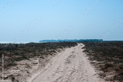 Countryside sandy road along sea beach dunes in summer day