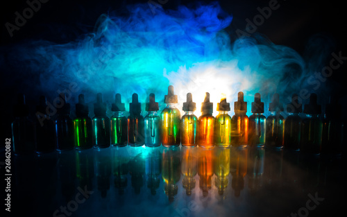 Vape concept. Smoke clouds and vape liquid bottles on dark background. Light effects. Useful as background or electronic cigarette advertisement.