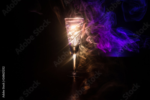 Closeup wine glass with fog at dark background. Beautiful glass with smoke and light.
