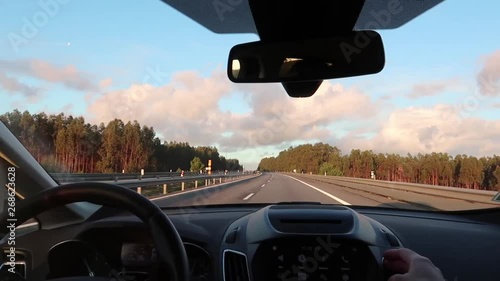 road view through car windshield, dashboard and steering wheel with driver's hands, concept of traveling by car