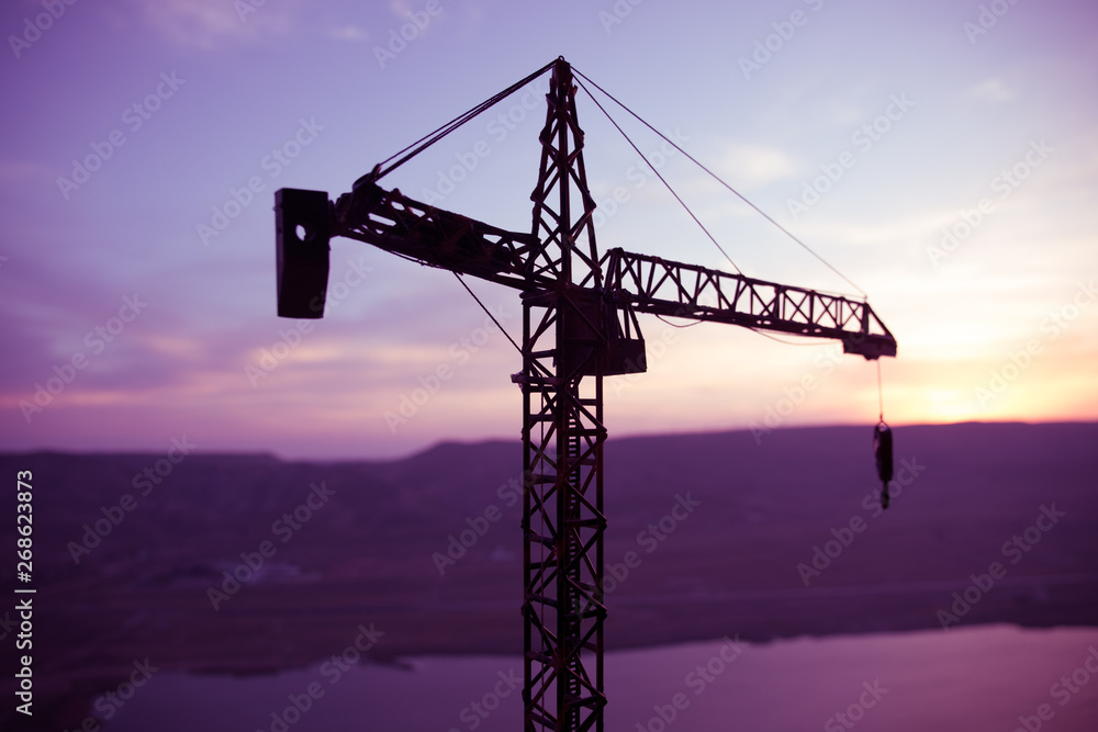 Abstract Industrial background with construction crane silhouette over amazing sunset sky. Tower crane against the evening sky. Industrial skyline