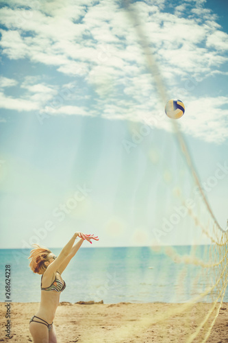 One young beautiful lady is playing volleyball on the beach, summer time on beach.