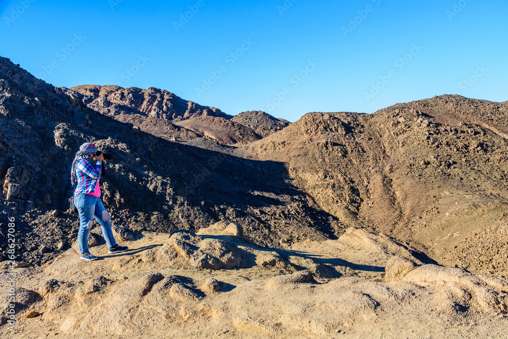 Young woman taking a photo in Arabian desert not far from the Hurghada city, Egypt Young woman taking a photo in Arabian desert not far from the Hurghada city, Egypt