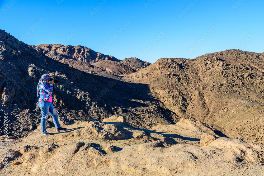 Young woman taking a photo in Arabian desert not far from the Hurghada city, Egypt