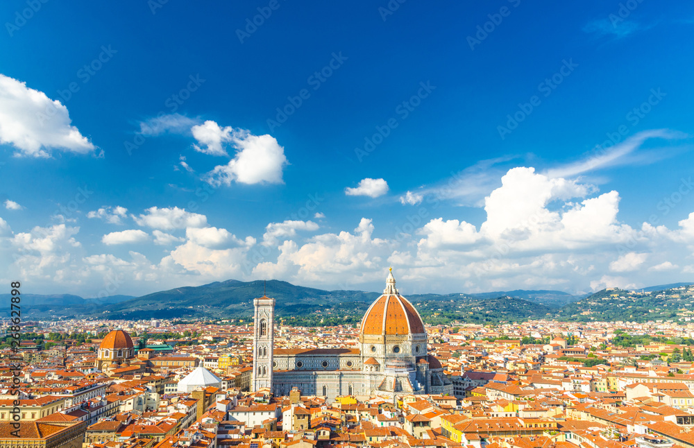 Obraz premium Top aerial panoramic view of Florence city with Duomo Cattedrale di Santa Maria del Fiore cathedral, buildings houses with orange red tiled roofs and blue sky white clouds, copy space, Tuscany, Italy