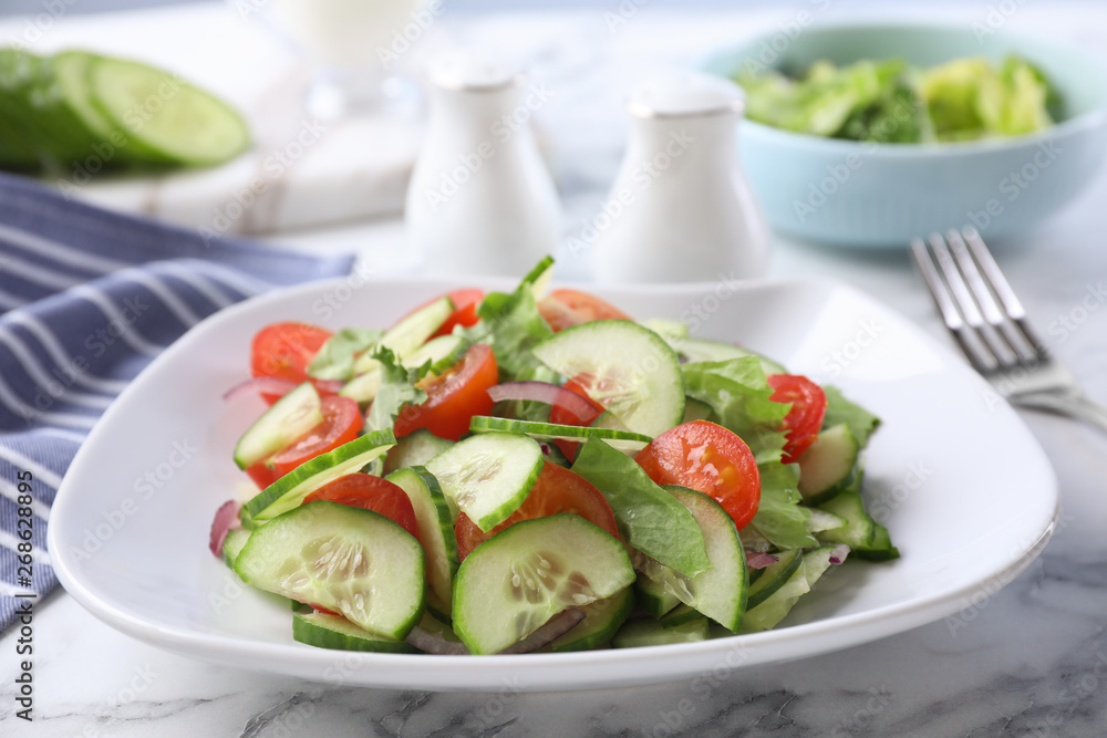 Plate of vegetarian salad with cucumber, tomato, lettuce and onion served on table, closeup Plate of vegetarian salad with cucumber, tomato, lettuce and onion served on table, closeup