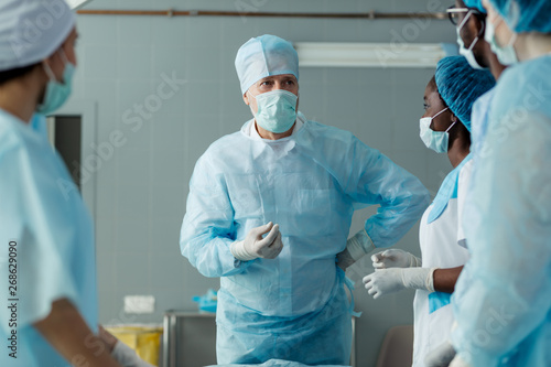 senoir doctor with hand on his having arguement with colleagues before surgery. close up photo