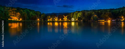 Landscape panorama with windmills at the blue hour in White Night of the Museums. Dumbrava lake  Astra Museum of Traditional Folk Civilization  Sibiu city  Romania