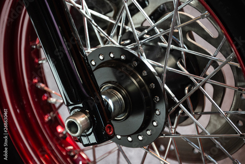 Detail of the black wheel of a customized motorcycle chromed with red and silver wheels