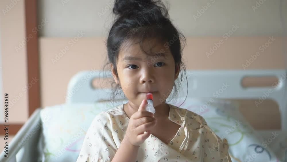 Asian child cute or kid girl Influenza sick holding and eating or taking sweet red drug or water medicine by syringe pump on bed at hospital room for pediatric patient treatment and healthcare on slow Asian child cute or kid girl Influenza sick holding and eating or taking sweet red drug or water medicine by syringe pump on bed at hospital room for pediatric patient treatment and healthcare on slow