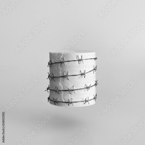 A roll of toilet paper wrapped in red barbed wire on a gray background. Strange funny joke.