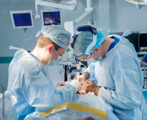 Spinal surgery. Group of surgeons in operating room with surgery equipment. Laminectomy