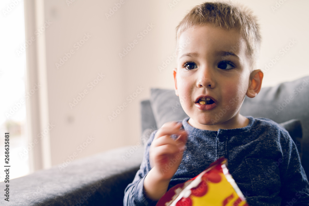 © Miljan Živković - Portrait of a little small boy eating unhealthy snacks corn peanut flips at home © Miljan Živković - Portrait of a little small boy eating unhealthy snacks corn peanut flips at home