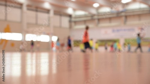 Unfocused scene of a group of children running and exercising in a sports pavilion with their school