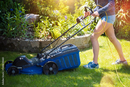 Photos belle jeune femme passant la tondeuse dans le jardin