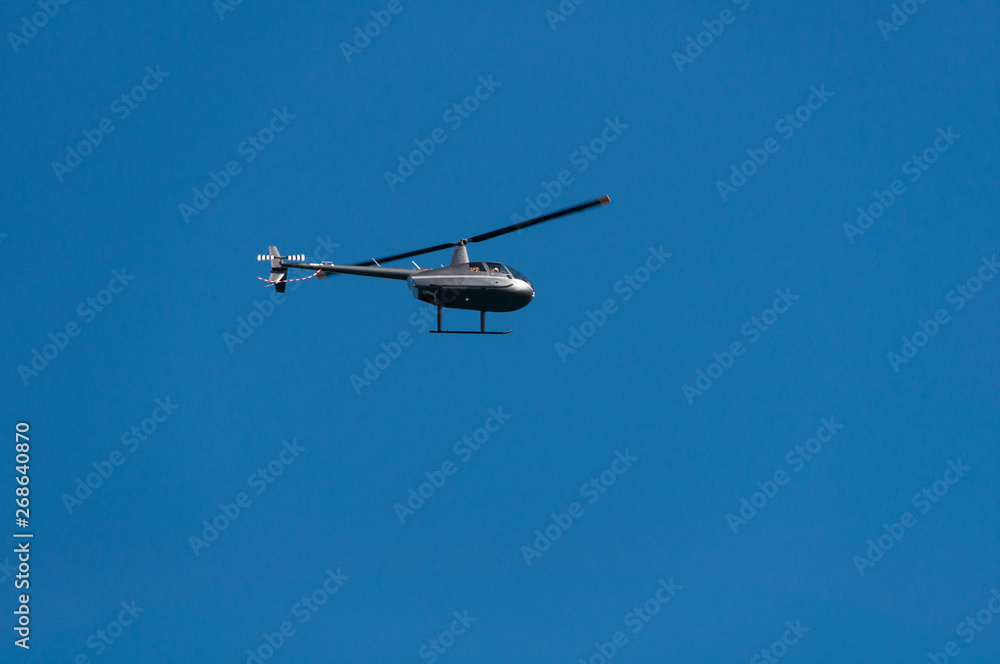 Helicopter flying against clear blue sky on the background