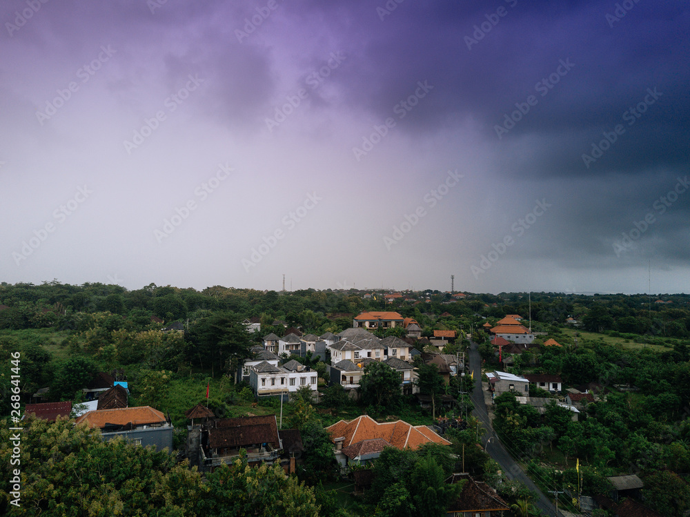 Drone cityscape and forest view. Asian homes and dark cloudy sky. High panorama from above