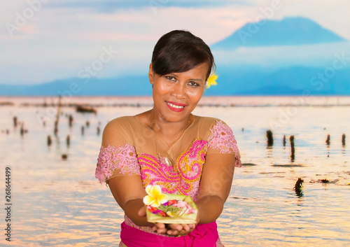 beautiful happy middle aged Indonesian Balinese woman in traditional ceremony dress at tropical beach with Bali Agung volcano background in holidays tourist destination photo