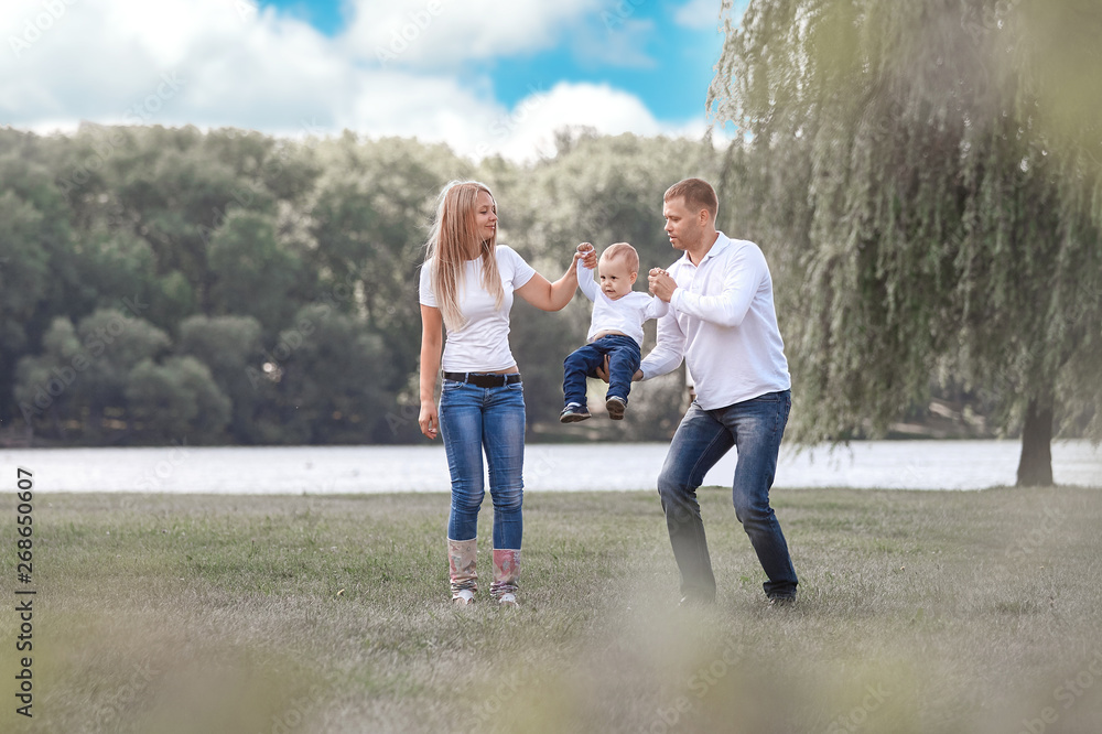 Fototapeta premium happy parents with their little son walking together in spring Park