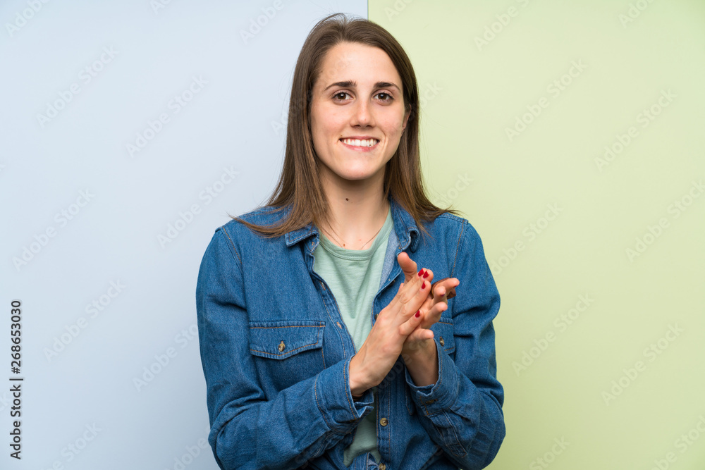Young woman over colorful background applauding Young woman over colorful background applauding
