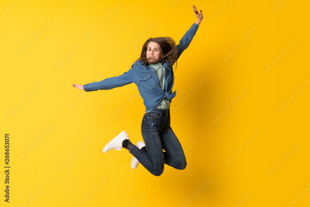 Young woman jumping over yellow background