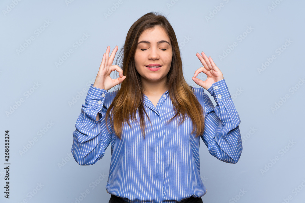 Young girl over isolated blue wall in zen pose Young girl over isolated blue wall in zen pose