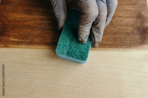 Plywood protection stain. Wood impregnation. Handwork. sponge treatment. Man painting wooden floor. Manual wood coating stain
